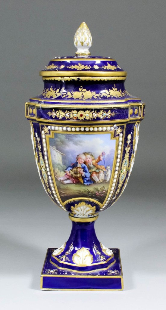 An impressive 19th century ‘Sèvres’ porcelain vase and cover with deep blue and gilt body enameled in colors with children playing a hurdy-gurdy. Except it’s a French copy and damaged – its handles are missing – reducing its saleroom value to £60– £80. The Canterbury Auction Galleries