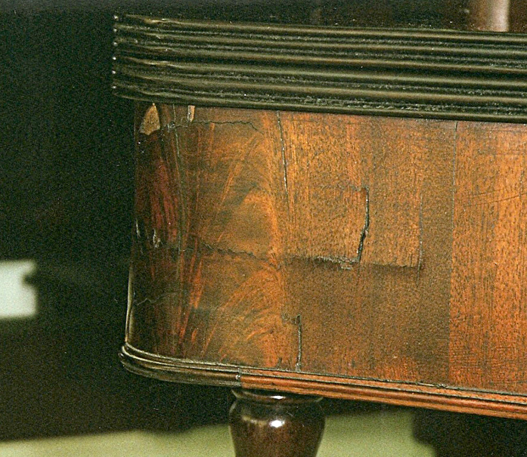 In this photo the solid wood underlayment has shrunk under the veneer of the skirt of this Federal-era fold-over game table telegraphing the damage to the surface.