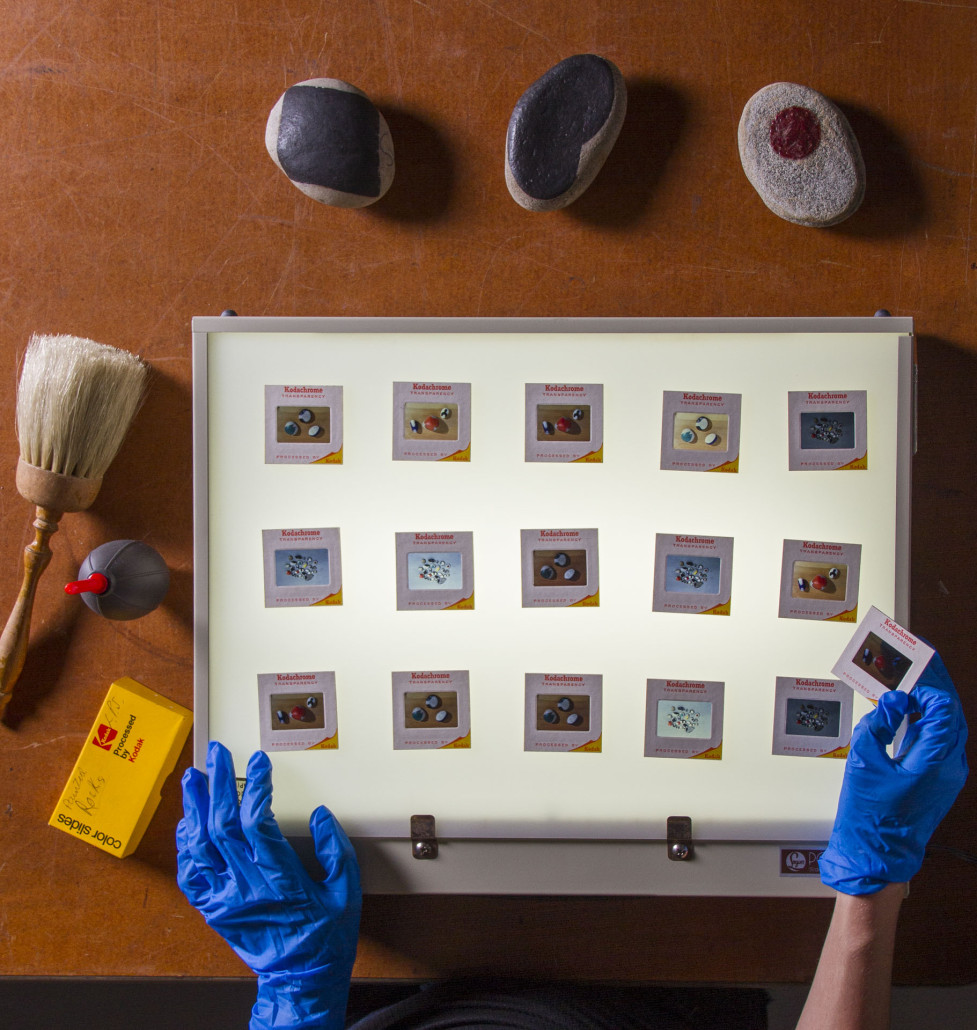 The three rocks painted by Leon Polk Smith are pictured at the top of the photo along with Kodak slides of the artist's collection. Myers Fine Art image