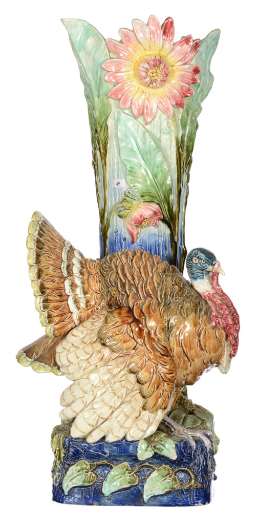 Majolica umbrella stand with gorgeous colors and a full-figure strutting tom turkey in front of large blossoming plants. Woody Auction image