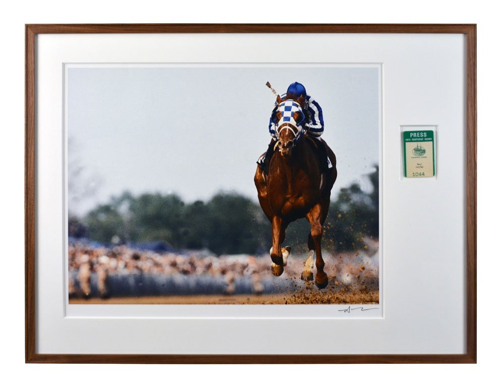 The spectacular 3-year-old thoroughbred Secretariat winning the 1973 Kentucky Derby. The signed photograph is handsomely matted and framed with Neil Leifer's press credential for the event. Guernsey’s image
