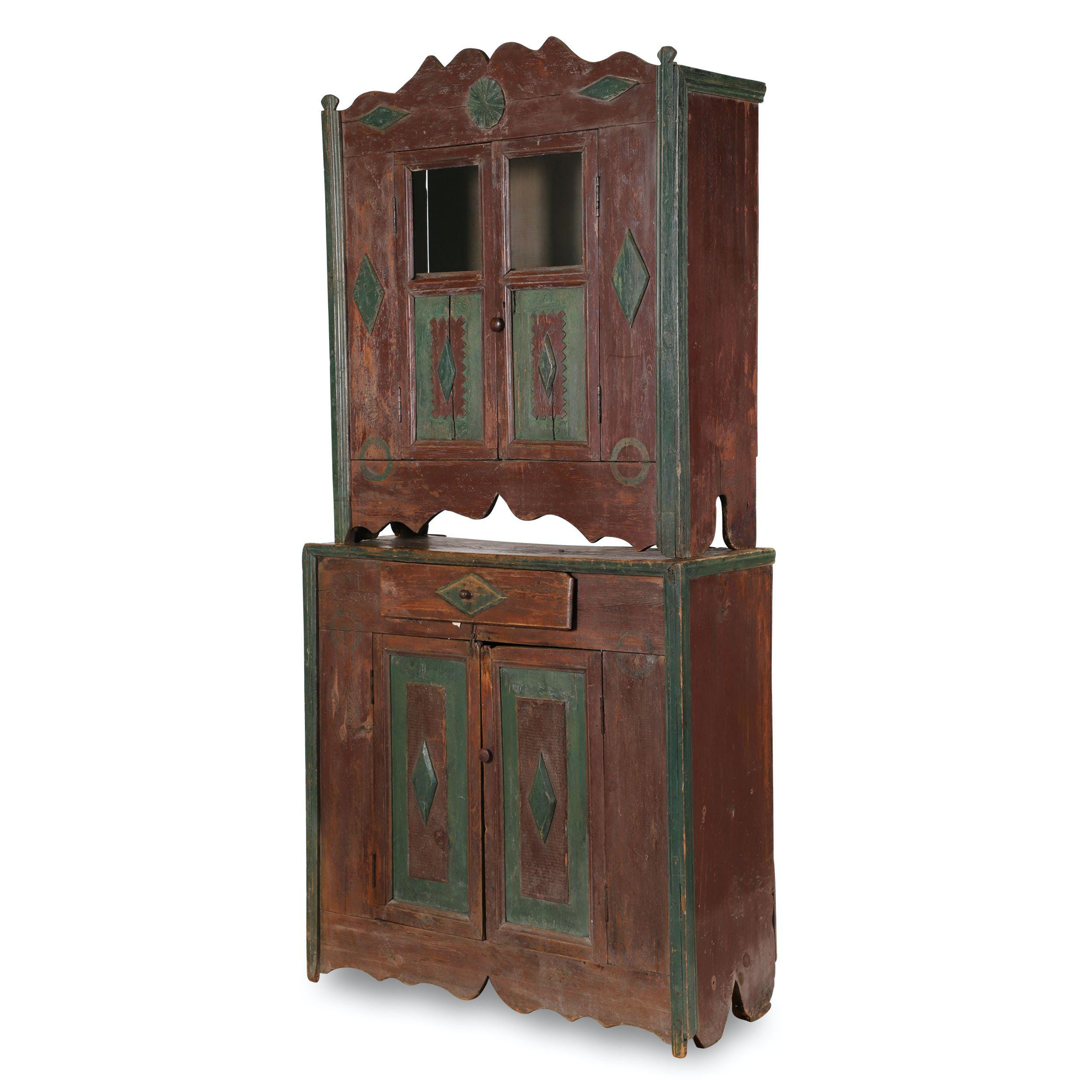 Western Canada Ukrainian two-piece cupboard in the original burgundy red paint with green Highlights, estimated at $2,000-$3,000.