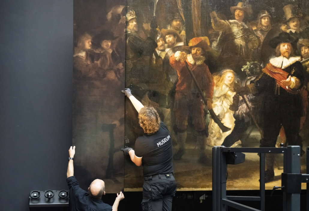 Rijksmuseum attendants install a restoration to the left side of Rembrandt’s ‘Night Watch’ to simulate a section that was cut away decades after it was painted. Photo credit: Rijksmuseum/Reinier Gerritsen