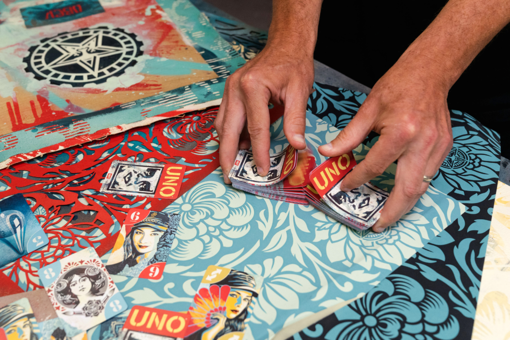 Fairey shuffling a deck of UNO Artiste Series cards featuring his artwork.
