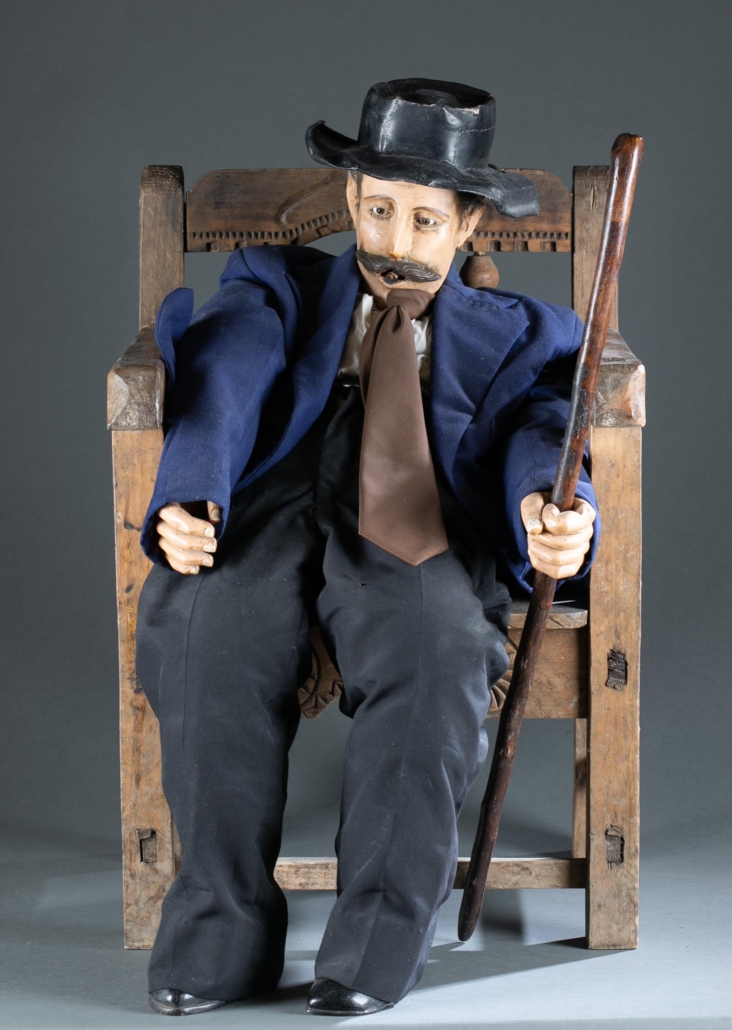 Maximon/San Simon figure in chair with offered cigar in mouth and holding walking stick, est. $1,000-$1,500