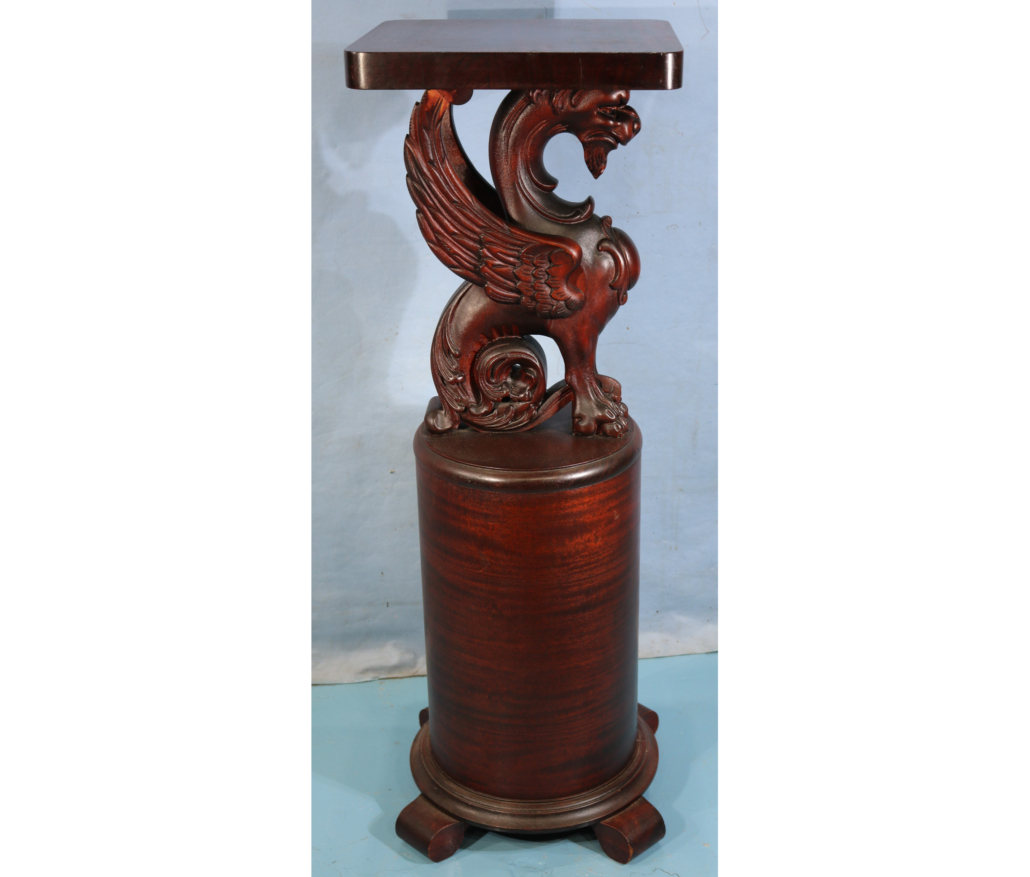 Solid mahogany round pedestal with winged griffin top, est. $1,500-$3,000