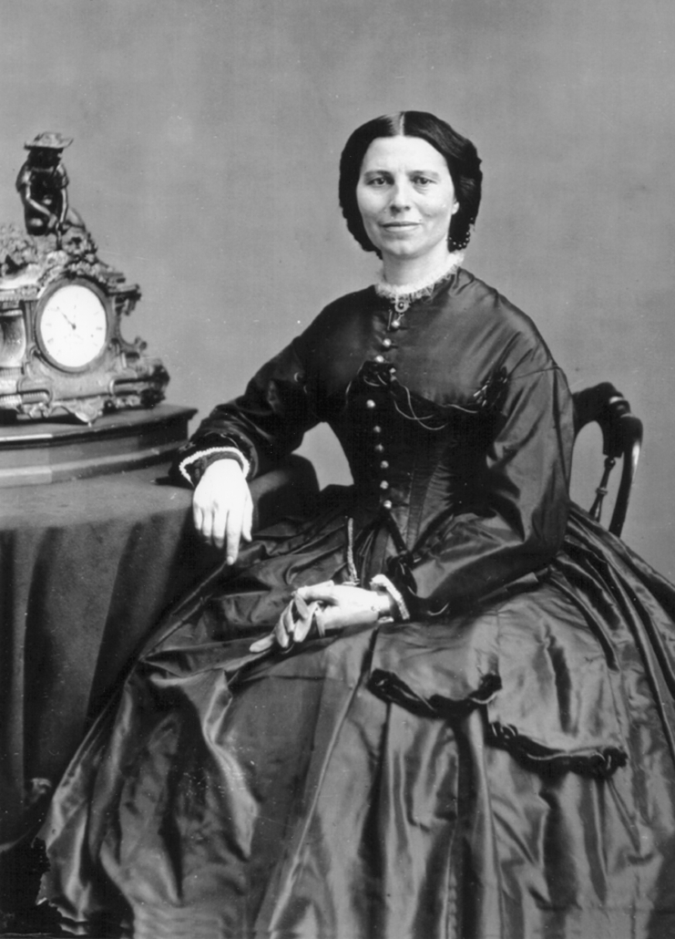 Mathew Brady, (1822-1896), Clara Barton. Photographic print from glass-plate negative, circa 1865. The honored American nurse is shown at about age 43, and her portrait includes the “Reaper” cast-metal mantel clock in the background.