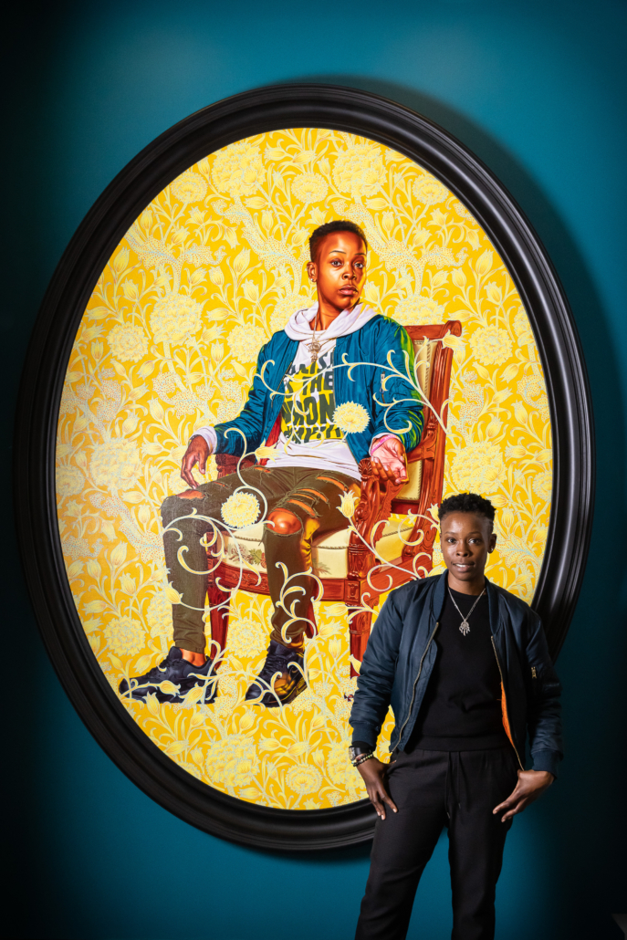 Melissa Thompson standing beside Kehinde Wiley's ‘Portrait of Melissa Thompson,’ 2020, now on display at the V&A (c) Victoria and Albert Museum