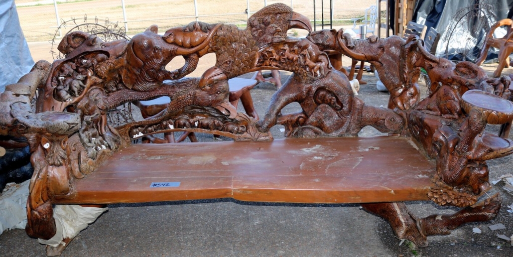Teakwood bench carved with an eagle, an elephant, a monkey, snakes and deer, est. $5,000-$10,000