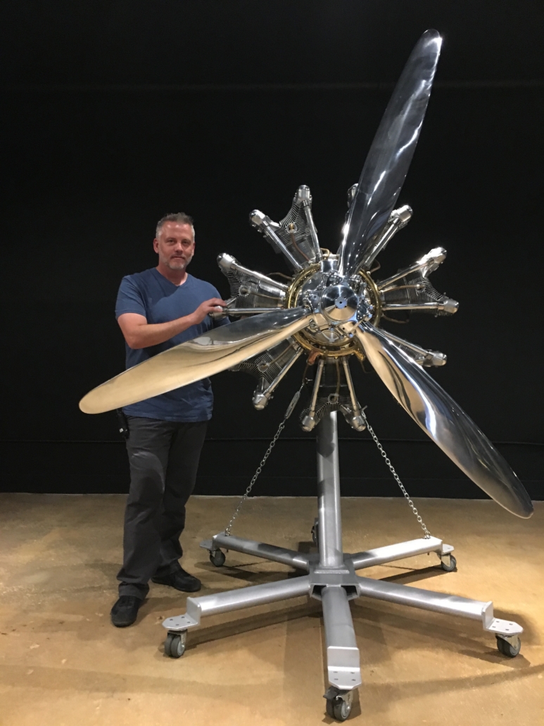 Arron Rimpley poses with a Jacobs seven-cylinder radial engine made in 1944. The fine example of industrial art, with its aluminum engine and steel cylinders, is a wonder of aviation technology and history. The work dates back to Rimpley’s previous gallery, The Whitley Collection. Image courtesy of Lion and Unicorn.