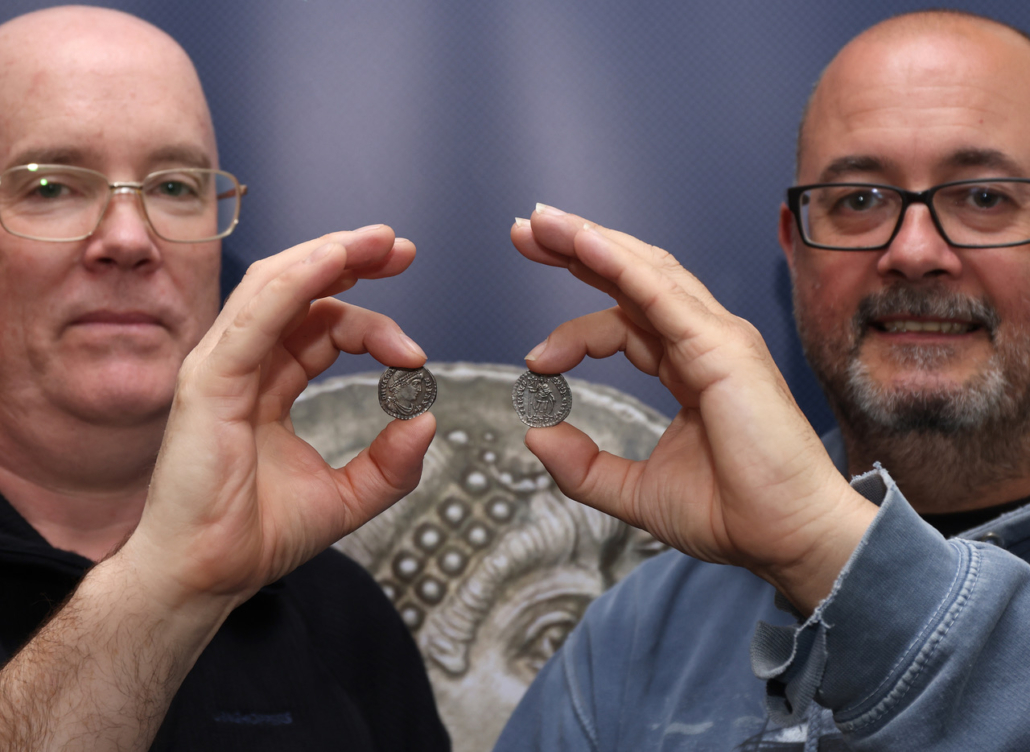Dave Allan (left) and Rob Abbott (right), two of the three men who discovered the Vale of Pusey hoard of Roman silver coins, pose with two examples. Image courtesy of Noonans