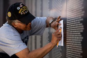 A veteran takes an impression of a name etched on the American Veterans Traveling Tribute (AVTT) Vietnam Wall, which will be displayed at the National WWI Museum and Memorial during Memorial Day Weekend 2022. Image courtesy of the National WWI Museum and Memorial