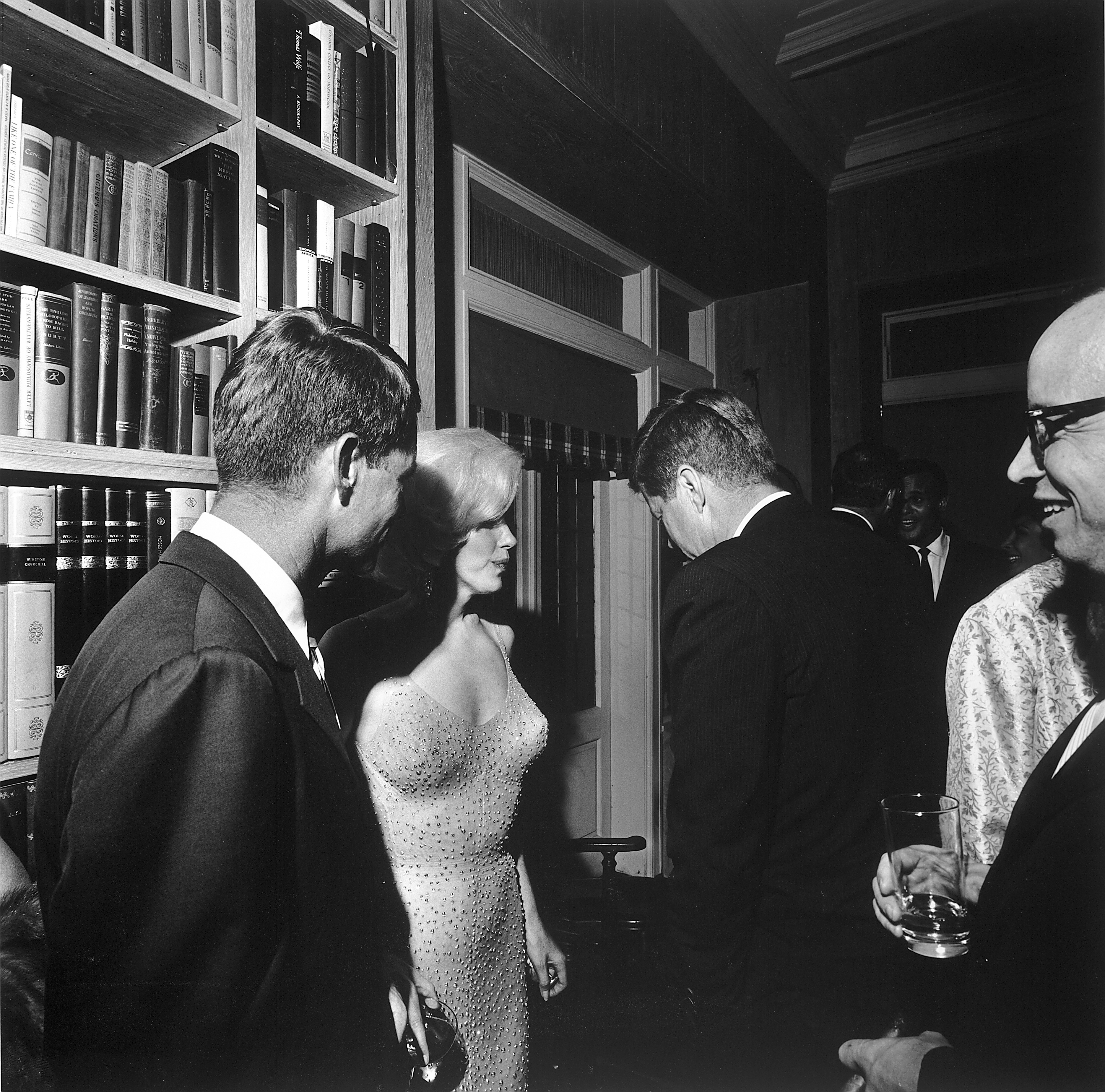 Marilyn Monroe shown wearing what would be dubbed the Happy Birthday, Mr. President dress in a photo taken by Cecil W. Stoughton on May 19, 1962 at Madison Square Garden in New York City. Robert Kennedy is at the far left, and President John F. Kennedy has his back to the camera. The current owner of the dress, Ripley’s Believe It Or Not!, is facing criticism for allowing Kim Kardashian to briefly wear it at the 2022 Met Gala, which some say caused damage to the famous garment. Image courtesy of Wikimedia Commons, which advises that it is in the public domain.