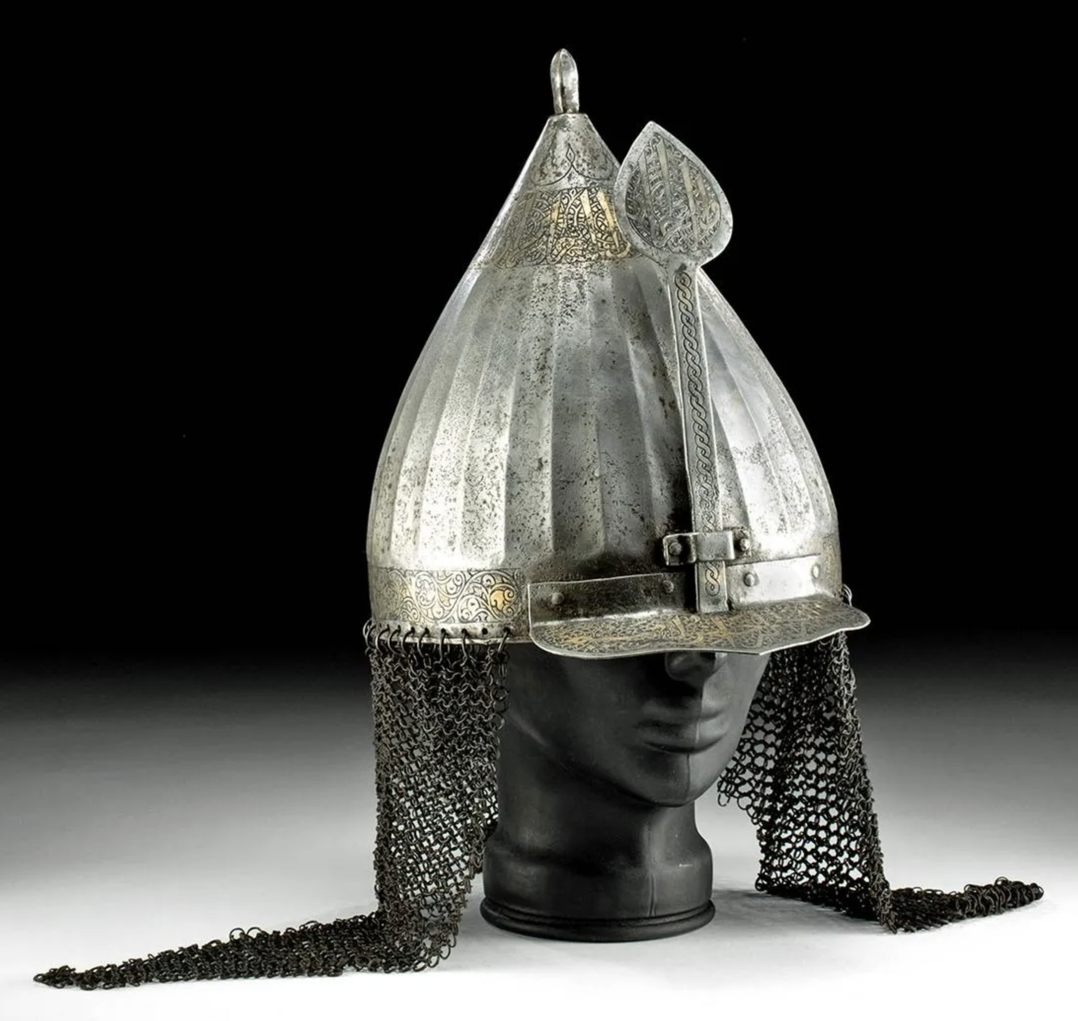 16th- to 17th-century CE Ottoman Empire (Turkey to Iran) gilded iron turban or chickhak helmet of classic pointed form with spiked finial, chainmail aventails suspended from loops, and calligraphic inscriptions. Similar to an example in Walters Art Museum collection. Provenance: Coral Gables, Florida private collection. Est. $30,000-$45,000. Courtesy of Artemis Gallery