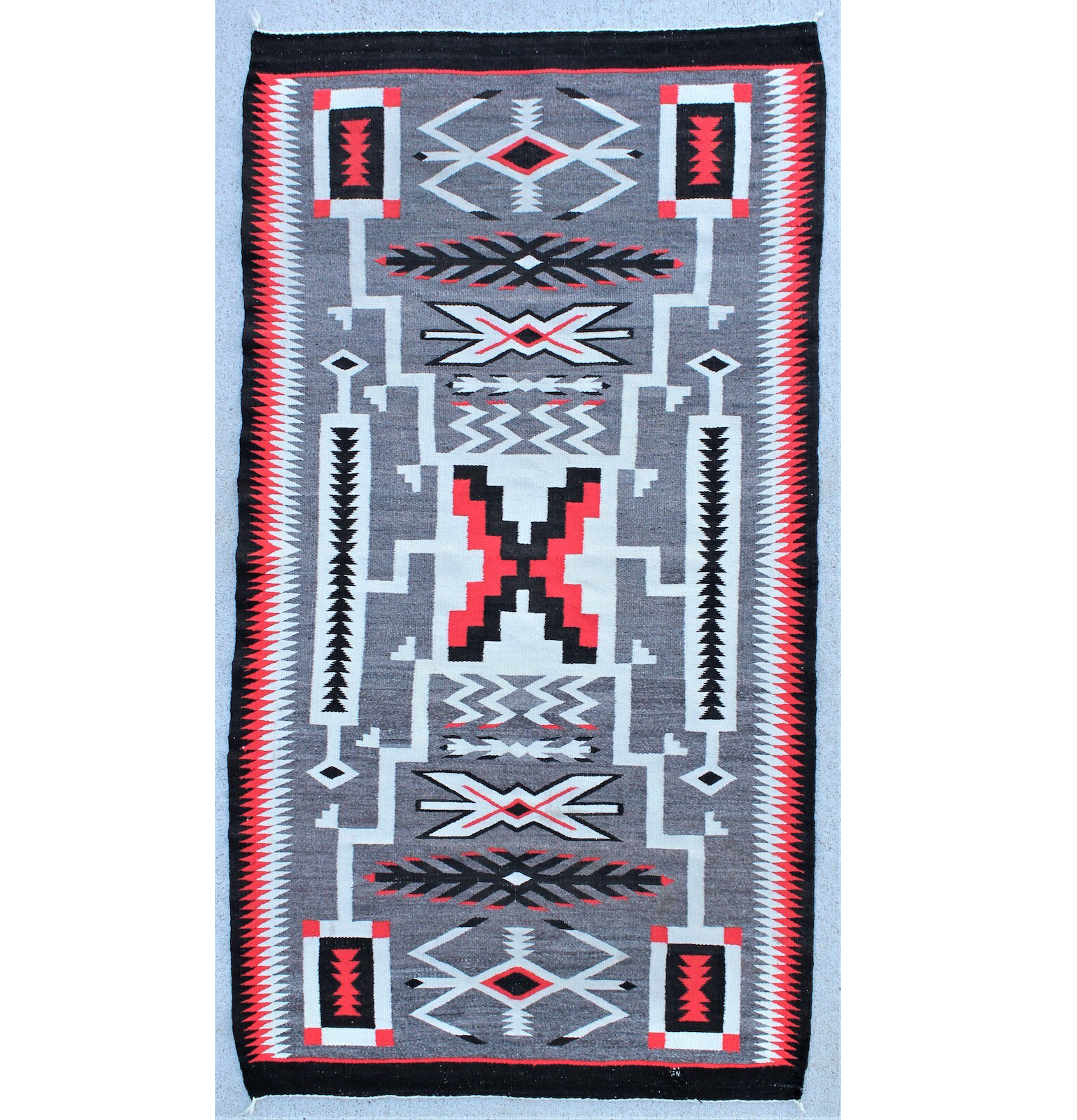 Extremely clean and colorful Navajo Crystal Storm weaving from the Four Corners region with J.B. Moore pattern incorporating waterbugs. Vivid red, black, white and gray motif, 33in x 61in, est. $1,200-$1,800