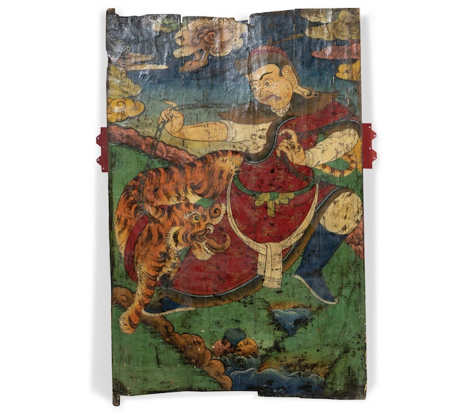 Tibetan polychrome painted wood door depicting a guardian spirit with a tiger on a chain in a celestial landscape, $17,500