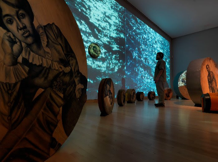 Whitfield Lovell, ‘Deep River,’ 2013. 56 wood discs, found objects, soil, video projections and sound. Size variable. 16 1/2 by 50 by 50ft. (2,500 sq. ft.) © Whitfield Lovell. Courtesy DC Moore Gallery, New York, and American Federation of Arts.