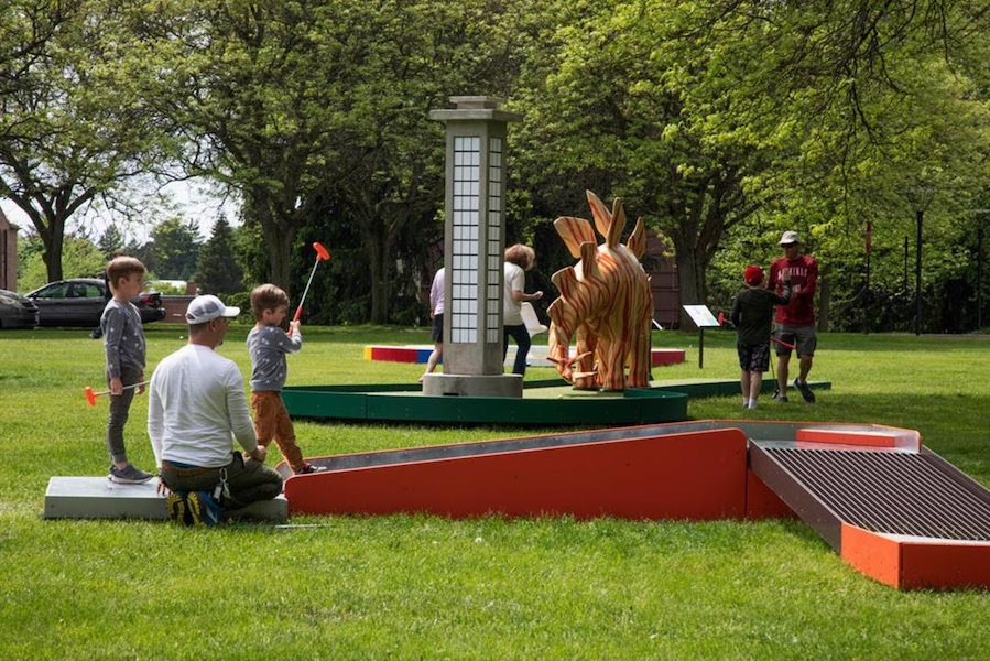 Family playing the Bertoia Bronze hole at Cranbrook on the Green, Summer 2022. Image courtesy of Cranbrook Art Museum, photo credit PD Rearick.